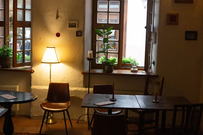 Tables under the windows, lit by a floor lamp